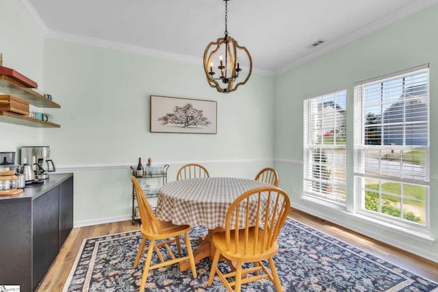 dining space featuring an inviting chandelier, ornamental molding, visible vents, a healthy amount of sunlight, and light wood finished floors