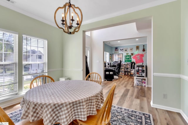 dining room with light wood-style floors, an inviting chandelier, and crown molding