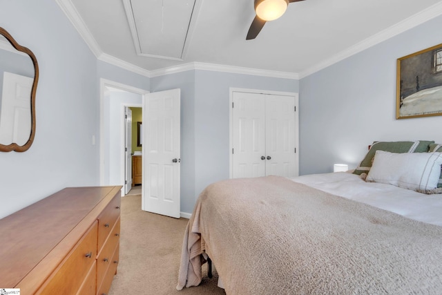 bedroom featuring a closet, ornamental molding, a ceiling fan, attic access, and light colored carpet