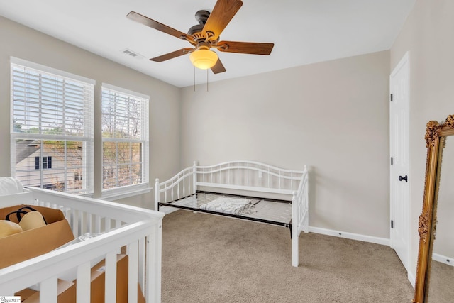 carpeted bedroom featuring baseboards, a ceiling fan, and visible vents
