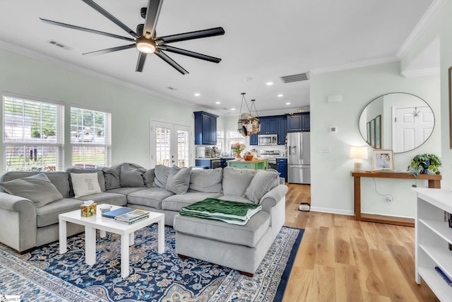 living room with visible vents, ceiling fan, ornamental molding, and light wood-style flooring