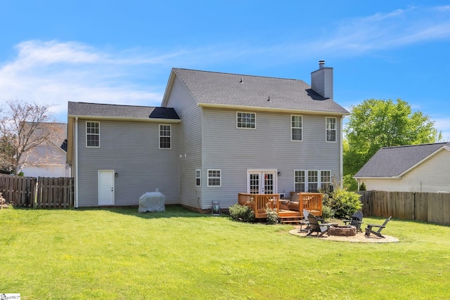 back of house with an outdoor fire pit, a chimney, fence, and a lawn