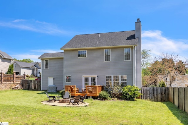back of house with a yard, a fenced backyard, a fire pit, and a chimney