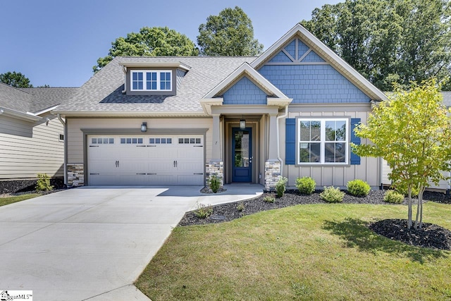craftsman inspired home with board and batten siding, roof with shingles, a front yard, a garage, and concrete driveway