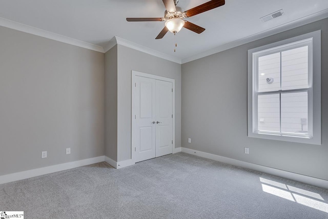 unfurnished bedroom with baseboards, ornamental molding, a closet, light carpet, and visible vents