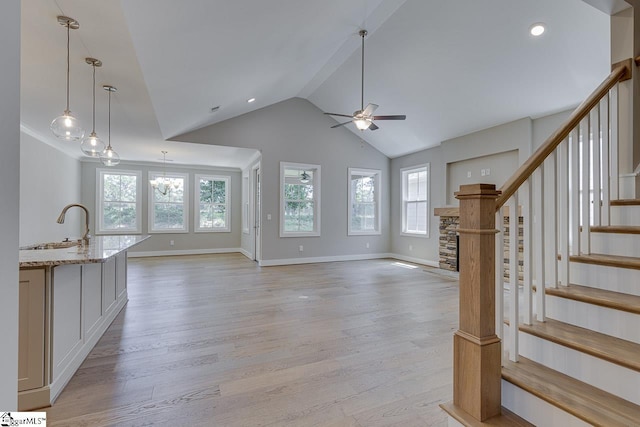 unfurnished living room with light wood finished floors, ceiling fan, a sink, and stairway