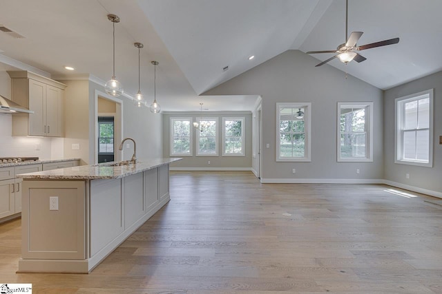 kitchen with a sink, open floor plan, light wood-type flooring, and stainless steel cooktop