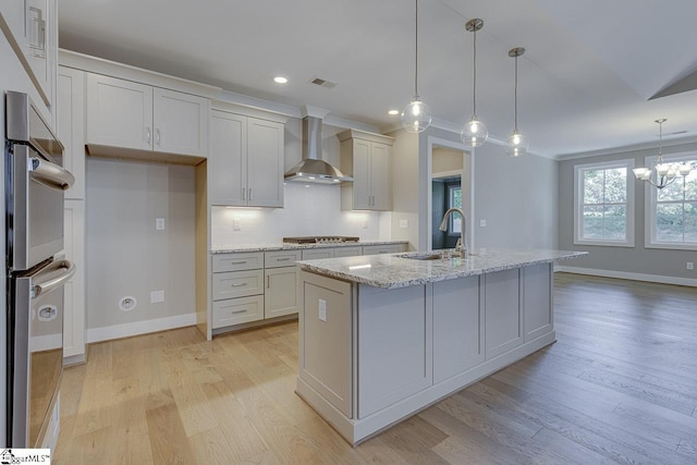 kitchen featuring tasteful backsplash, visible vents, wall chimney exhaust hood, a sink, and stainless steel appliances