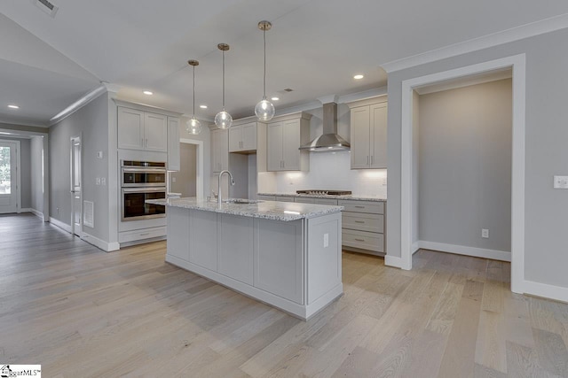kitchen featuring a sink, wall chimney range hood, crown molding, stainless steel appliances, and backsplash