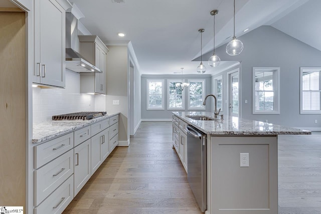 kitchen featuring a wealth of natural light, a sink, wall chimney range hood, and stainless steel appliances