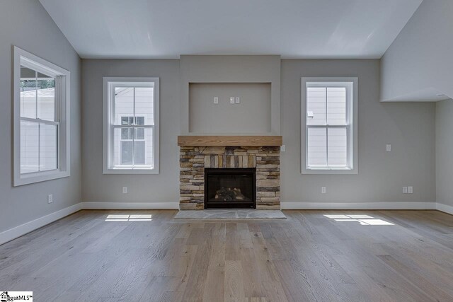 unfurnished living room featuring wood finished floors, baseboards, and plenty of natural light