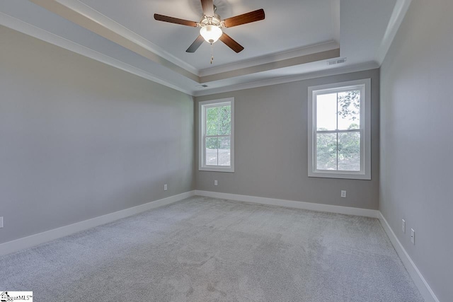unfurnished room featuring light colored carpet, ornamental molding, visible vents, a raised ceiling, and baseboards