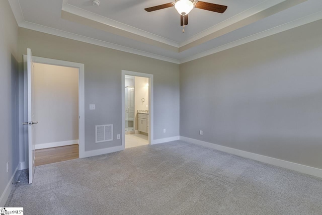 unfurnished bedroom featuring a raised ceiling, light colored carpet, baseboards, and visible vents