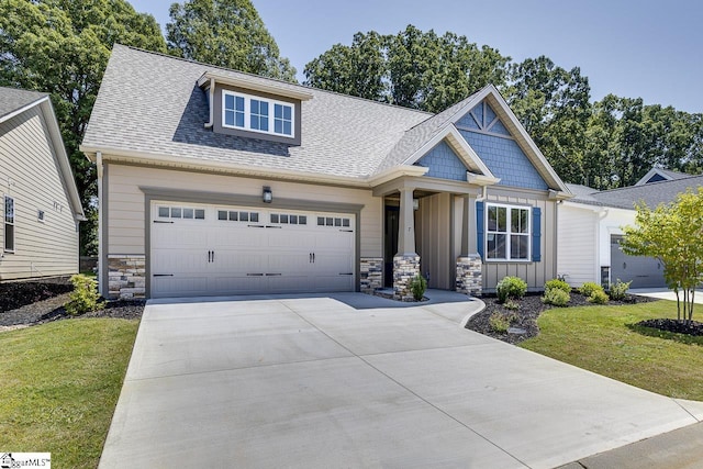 craftsman-style home featuring board and batten siding, stone siding, a front lawn, a shingled roof, and concrete driveway