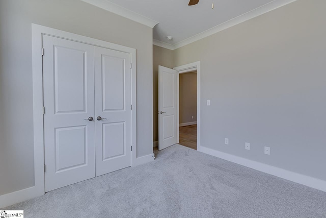unfurnished bedroom with baseboards, a closet, crown molding, carpet floors, and ceiling fan