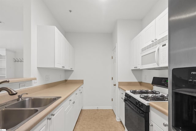 kitchen featuring stainless steel refrigerator with ice dispenser, a sink, white microwave, white cabinetry, and gas range oven