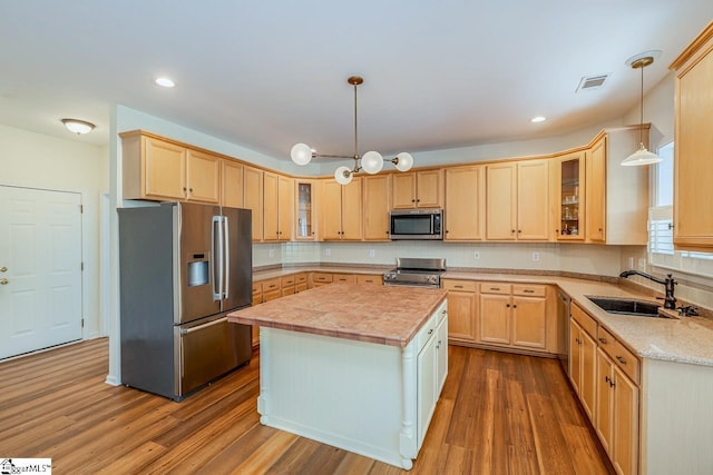 kitchen with stainless steel appliances, visible vents, a sink, and light brown cabinetry