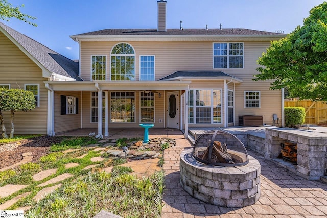 rear view of property with an outdoor fire pit, a chimney, a patio area, and fence