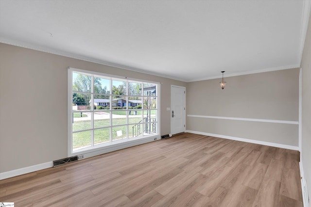 empty room with ornamental molding, visible vents, light wood-style flooring, and baseboards