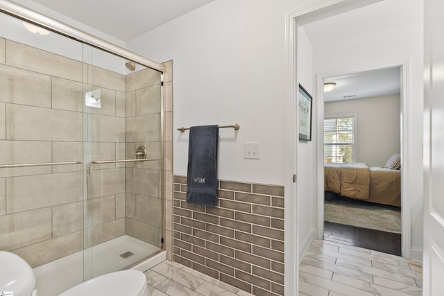 full bath with tile walls, toilet, a shower stall, and marble finish floor
