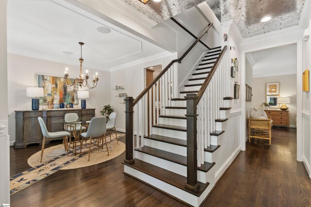 stairs featuring crown molding, wood finished floors, and an inviting chandelier