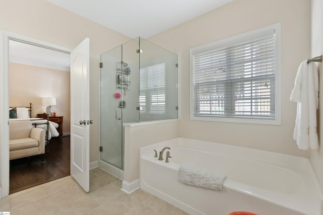 ensuite bathroom featuring a shower stall, a bath, ensuite bath, tile patterned flooring, and baseboards