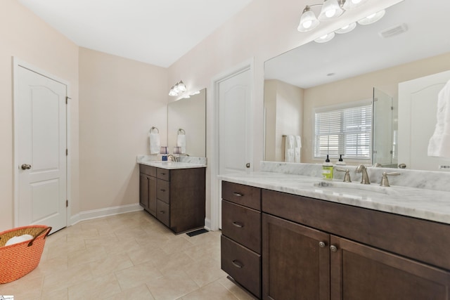 bathroom featuring two vanities, baseboards, tile patterned floors, visible vents, and a sink