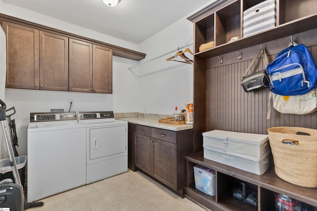 washroom with light tile patterned floors, washer and clothes dryer, and cabinet space