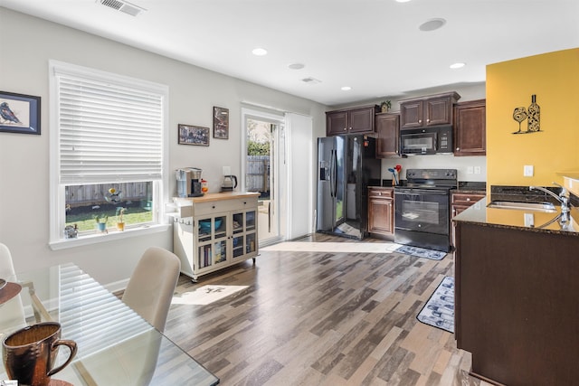 122 Barred Owl Dr, Fountain Inn, SC 29644 - kitchen with visible vents, a sink, dark brown cabinets, black appliances, and light wood-style flooring