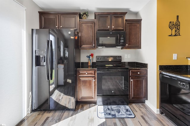 122 Barred Owl Dr, Fountain Inn, SC 29644 - kitchen with dark brown cabinetry, baseboards, dark stone countertops, light wood finished floors, and black appliances