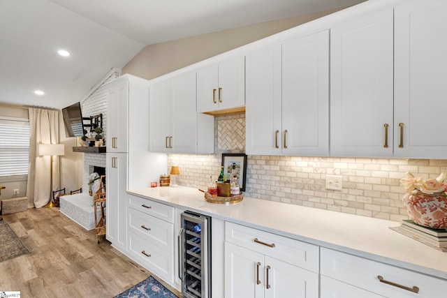 kitchen with light wood-type flooring, light countertops, beverage cooler, and lofted ceiling
