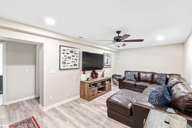 living room featuring baseboards, light wood-style flooring, visible vents, and a ceiling fan