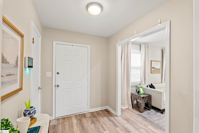 foyer entrance with light wood-style flooring and baseboards