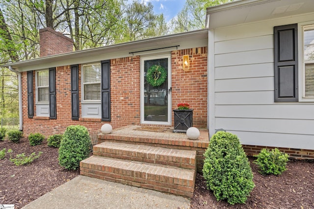 entrance to property featuring brick siding and a chimney