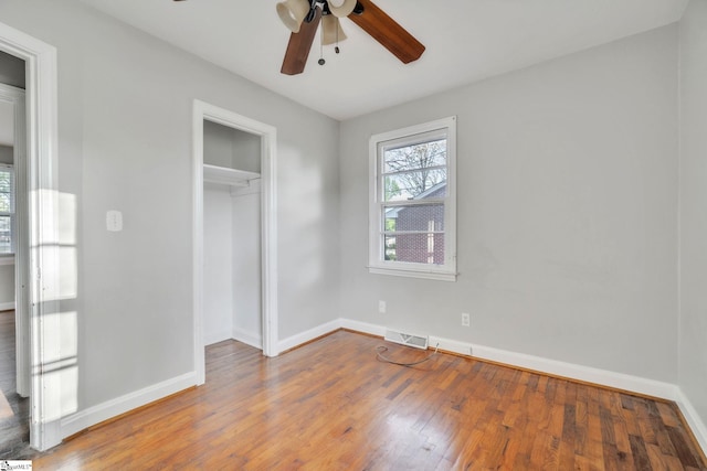 unfurnished bedroom with hardwood / wood-style floors, a closet, baseboards, and visible vents