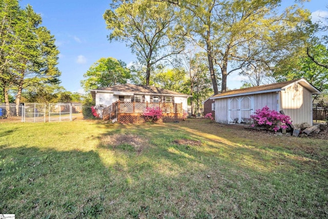 view of yard with an outbuilding, a wooden deck, a storage shed, fence, and a gate