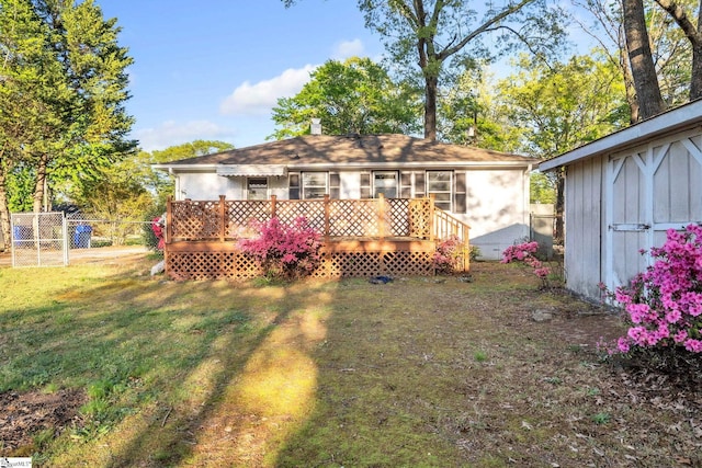 back of house featuring a yard, a storage shed, fence, an outbuilding, and a wooden deck