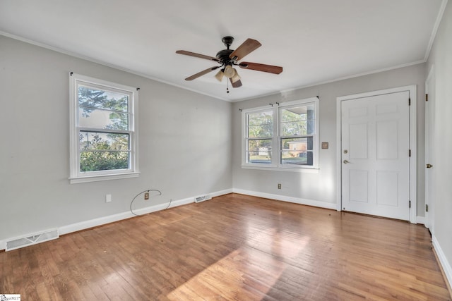 empty room featuring crown molding, wood finished floors, a ceiling fan, and visible vents
