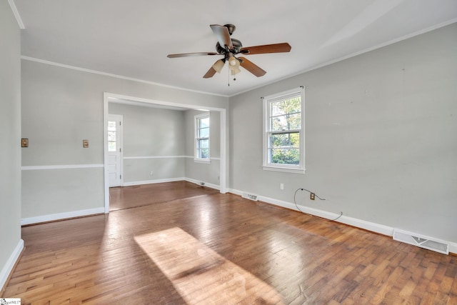 empty room with baseboards, ornamental molding, a ceiling fan, visible vents, and hardwood / wood-style flooring