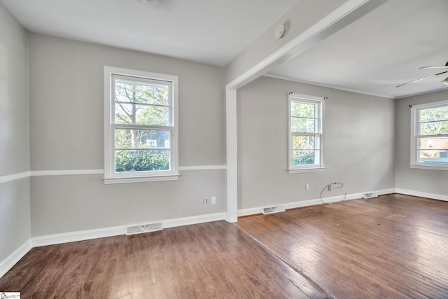 spare room featuring wood finished floors, ceiling fan, baseboards, and visible vents
