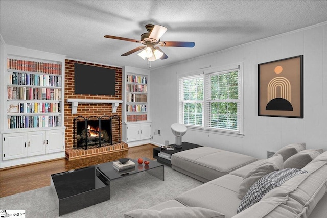 living area with a textured ceiling, a fireplace, a ceiling fan, and built in shelves