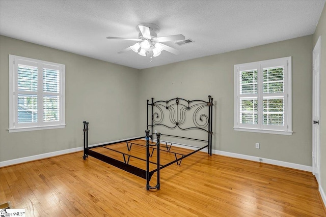 unfurnished bedroom with visible vents, baseboards, light wood finished floors, and a textured ceiling