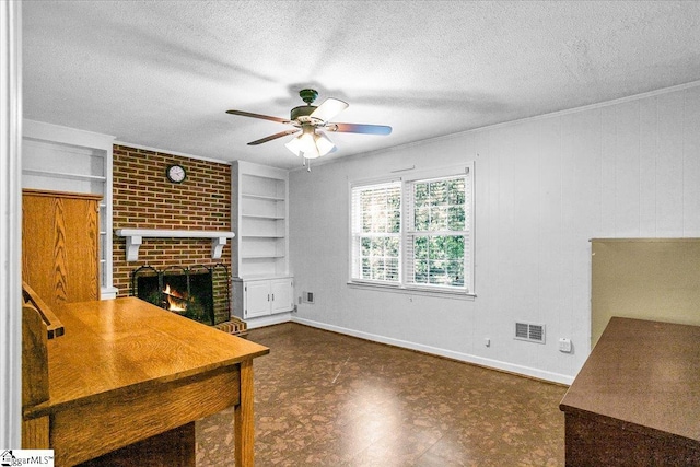 unfurnished office with a fireplace, tile patterned floors, a textured ceiling, visible vents, and ceiling fan
