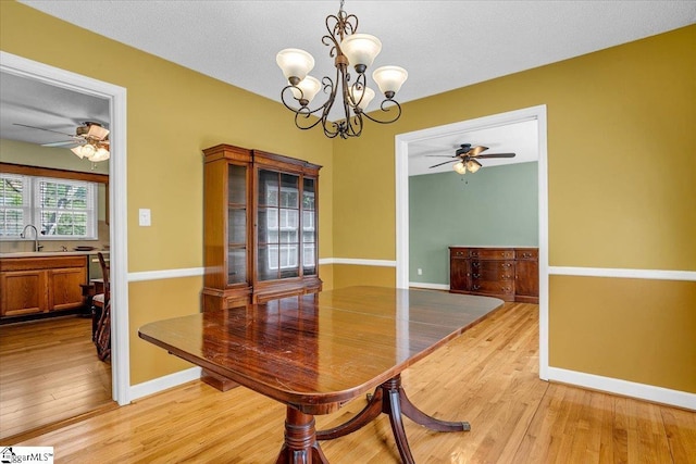 dining room featuring baseboards, light wood-style floors, and ceiling fan with notable chandelier
