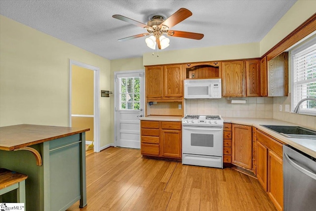 kitchen with light wood-type flooring, white appliances, open shelves, decorative backsplash, and a sink
