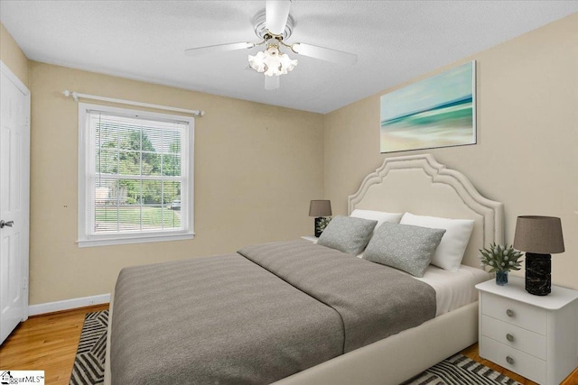bedroom with light wood-style floors, baseboards, and a ceiling fan