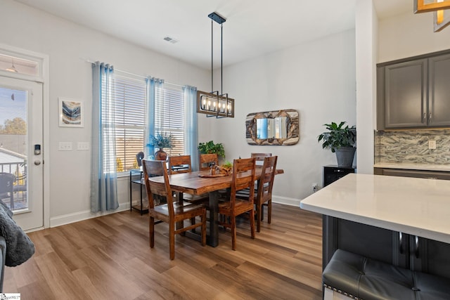 dining space featuring baseboards, visible vents, light wood-type flooring, and an inviting chandelier