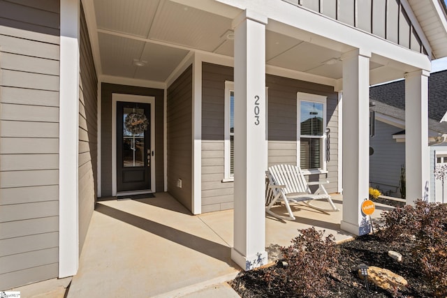 property entrance with board and batten siding and a porch