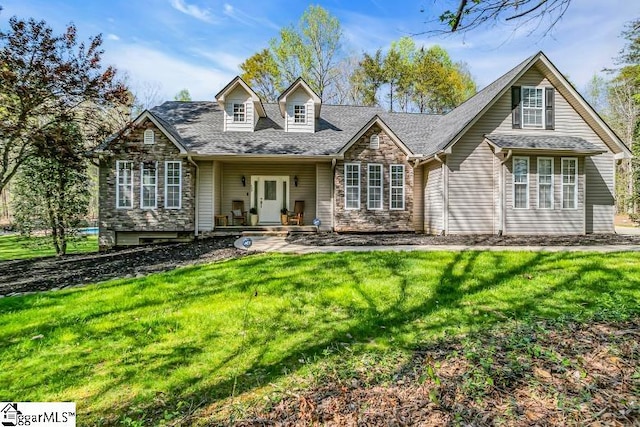 view of front of property with a front yard, a shingled roof, and stone siding