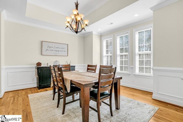 dining room featuring a chandelier, a raised ceiling, and crown molding